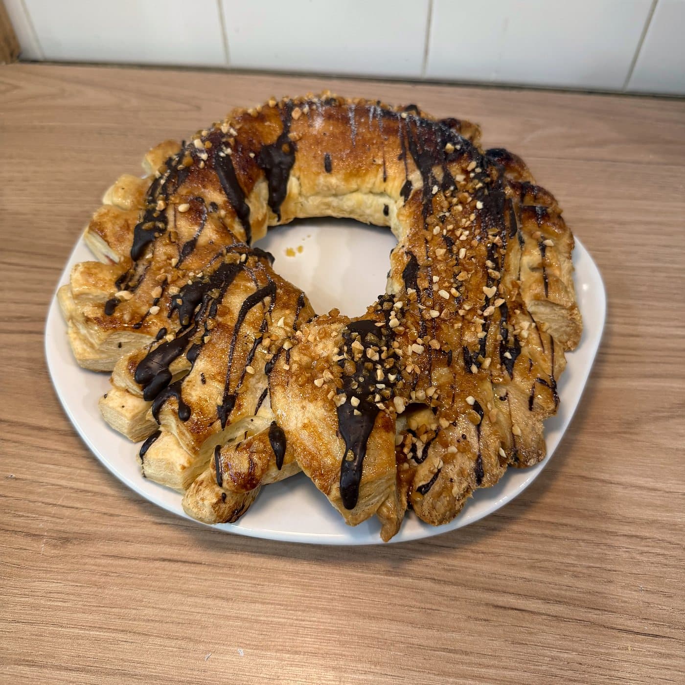 Cremona rellena de membrillo en forma de corona, con hilos de chocolate y frutos secos picados, sobre un plato
