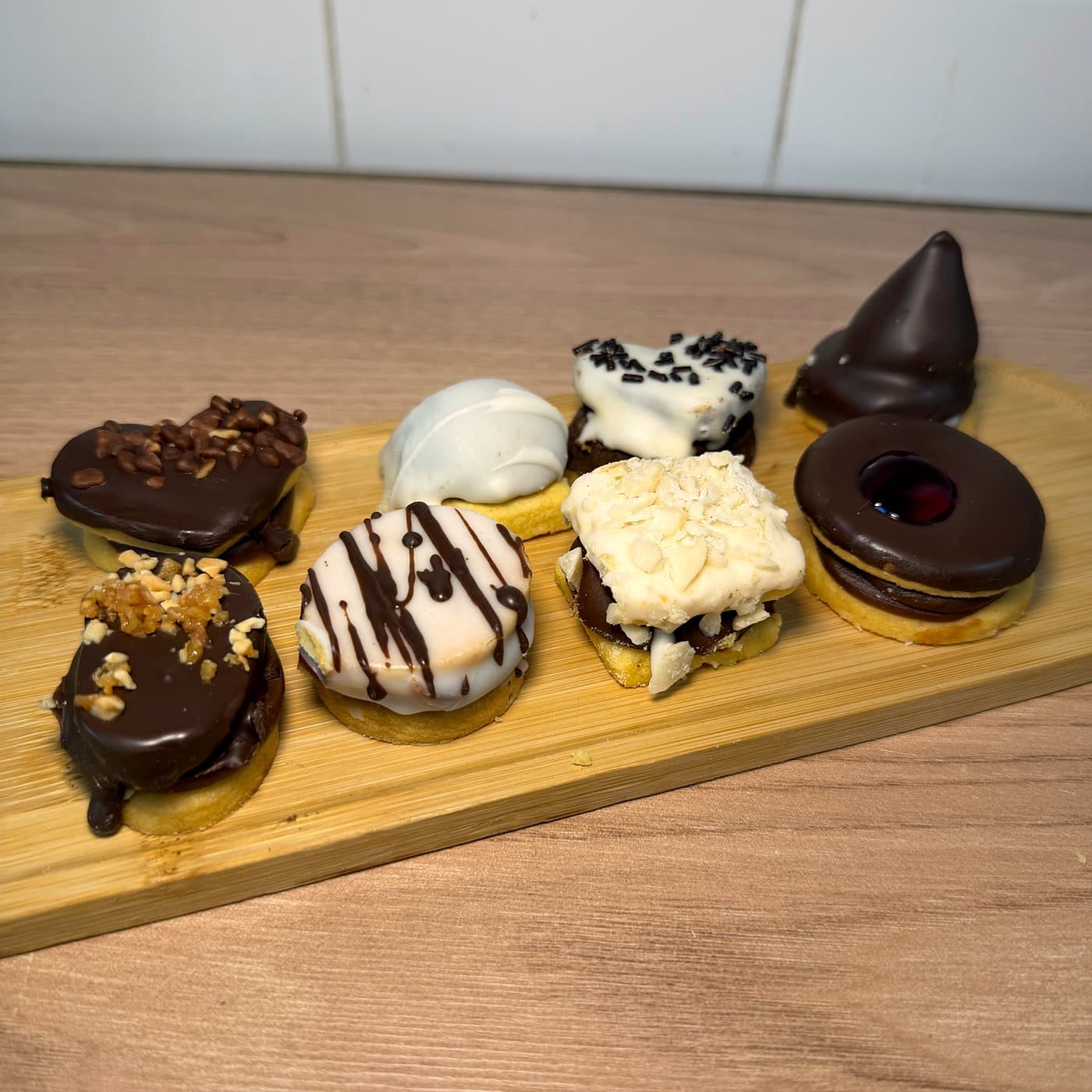 Masas secas surtidas sobre una tabla: bañadas en chocolate, en chocolate blanco y con mermelada