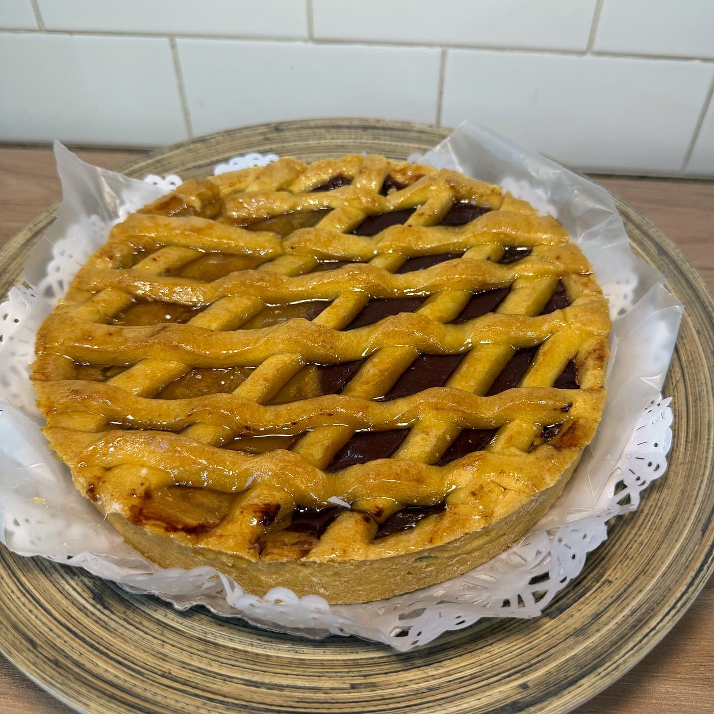 Pastafrola entera con enrejado de masa, sobre un plato con puntilla