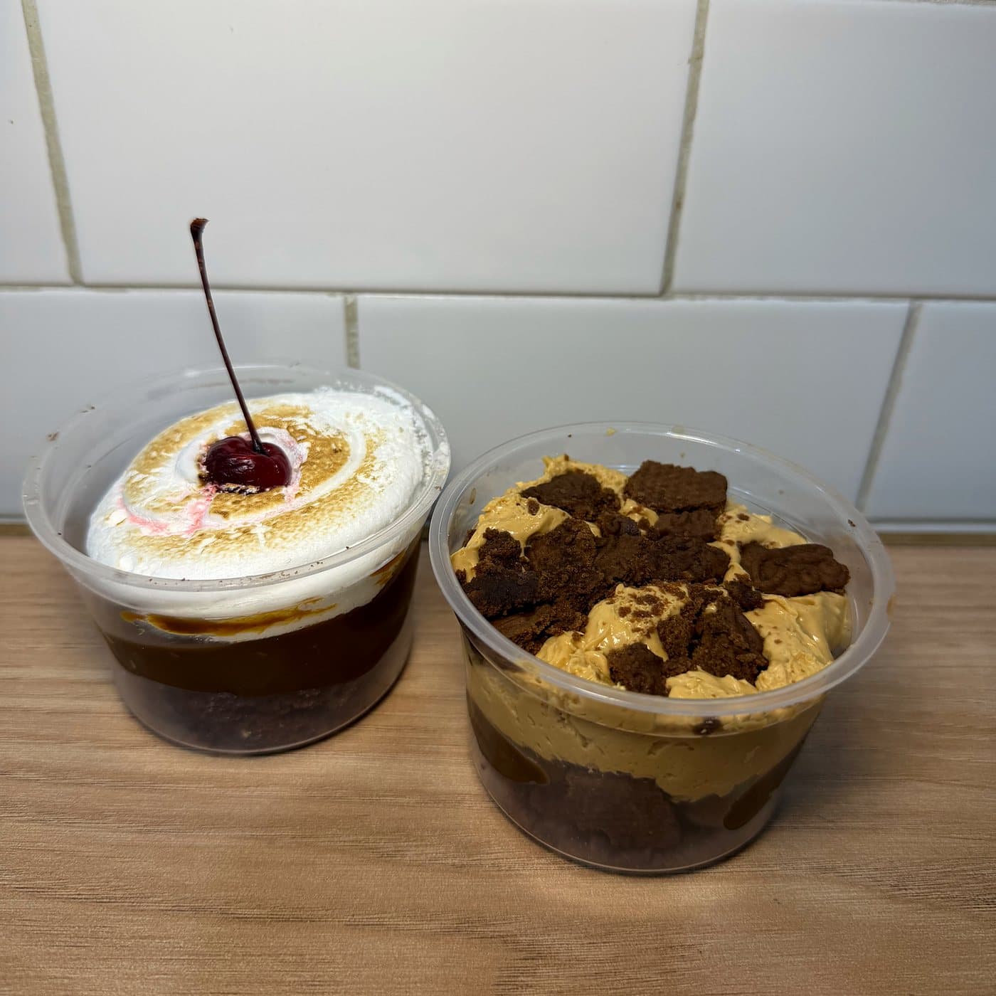 Dos postrecitos en vaso: uno con crema y una cereza, otro con trozos de chocolate